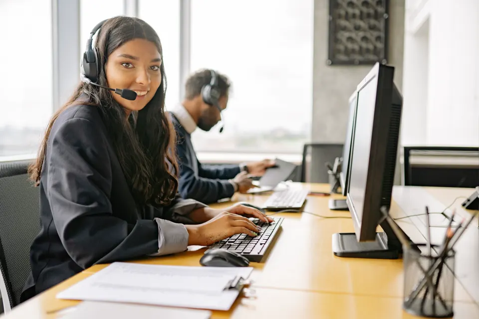 A call-centre floor with adults at headsets.