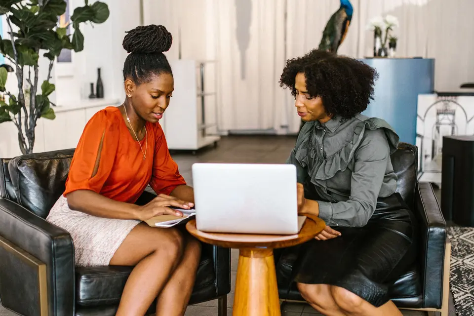 Two women on a sofa working together on a laptop.